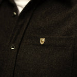 Courageous Love Pin in 14k gold vermeil with shield and heart design, worn on a dark grey wool shirt symbolizing strength, resilience, and love.