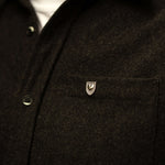 Courageous Love Pin in sterling silver with shield and heart design, worn on a dark grey wool shirt, symbolizing strength, resilience, and love.