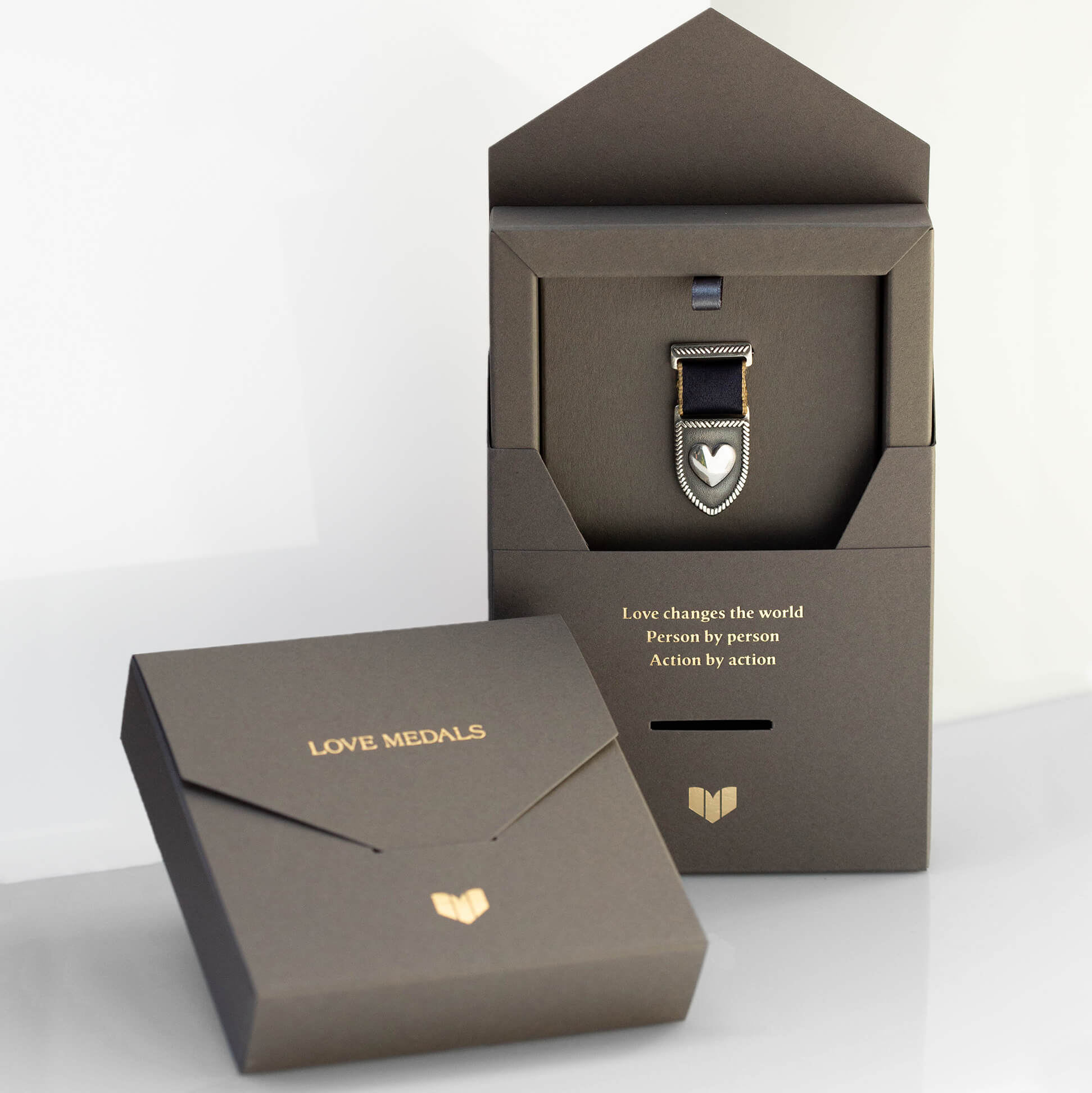 Sterling silver Love Medal with shield and heart design, displayed in elegant Love Medals gift box with certificate and the message "Love changes the world. Person by person. Action by action."